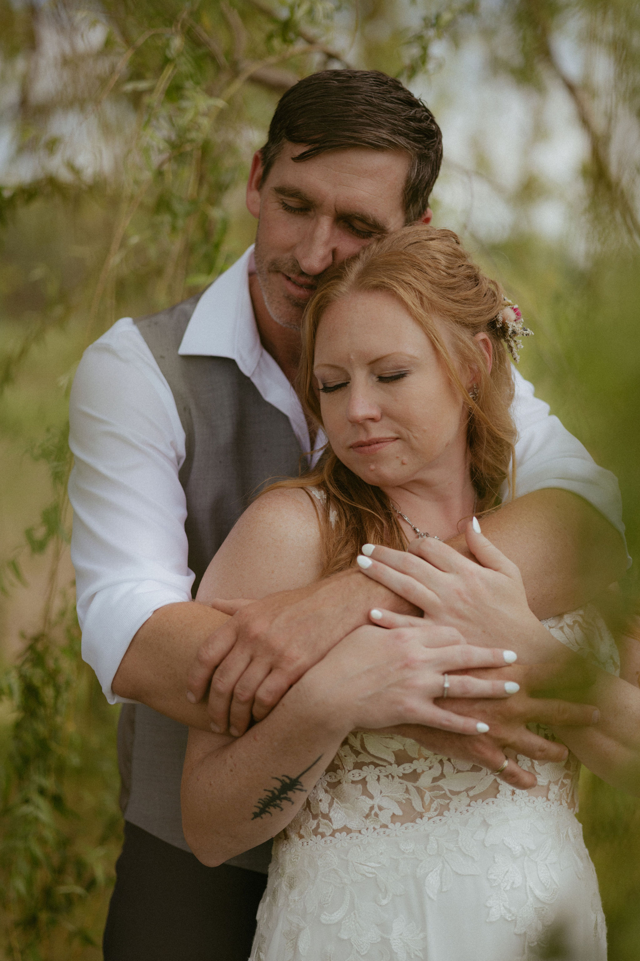 A husband and wife's left hands resting on a bouquet, showing their new wedding rings.